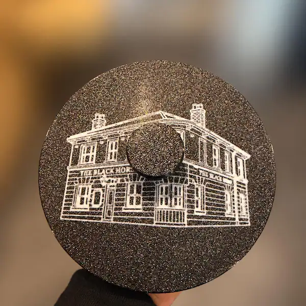Black sponge holder lid with white pub artwork and a screw-in handle