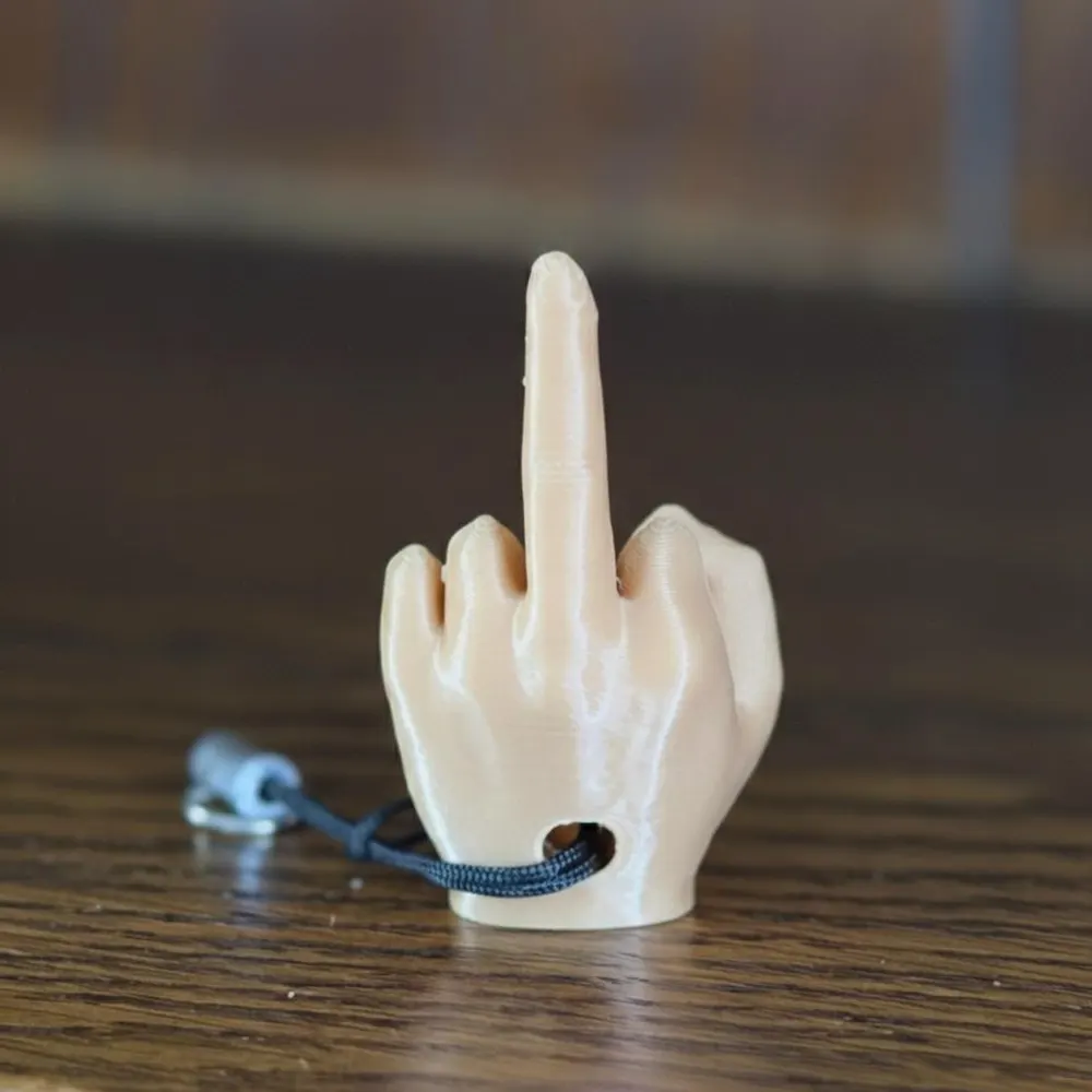 White 3D-printed middle finger keyring on a wooden surface